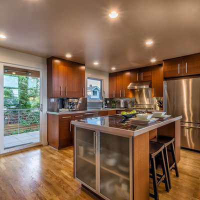 Inspiration for a mid-sized contemporary l-shaped medium tone wood floor and brown floor open concept kitchen remodel in Seattle with an undermount sink, flat-panel cabinets, dark wood cabinets, tile countertops, metallic backsplash, metal backsplash, stainless steel appliances and an island