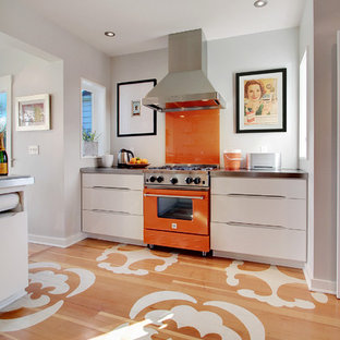 Esempio di una cucina minimal chiusa con ante lisce, ante bianche, paraspruzzi arancione, paraspruzzi con lastra di vetro, elettrodomestici colorati, top in zinco, pavimento in legno verniciato e pavimento multicolore