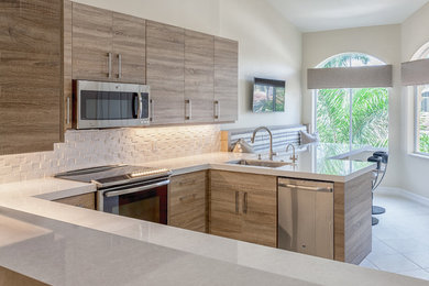 Mid-sized minimalist kitchen photo in Miami with an undermount sink, flat-panel cabinets, light wood cabinets, quartzite countertops, white backsplash and stainless steel appliances