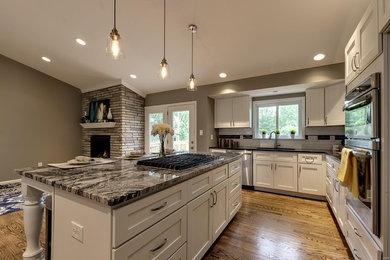Open concept kitchen - mid-sized transitional l-shaped dark wood floor and brown floor open concept kitchen idea in St Louis with a double-bowl sink, shaker cabinets, white cabinets, white backsplash, subway tile backsplash, stainless steel appliances, an island and gray countertops