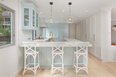 Example of a large transitional u-shaped light wood floor and beige floor eat-in kitchen design in Sydney with a farmhouse sink, shaker cabinets, blue cabinets, quartz countertops, white backsplash, subway tile backsplash, paneled appliances and gray countertops