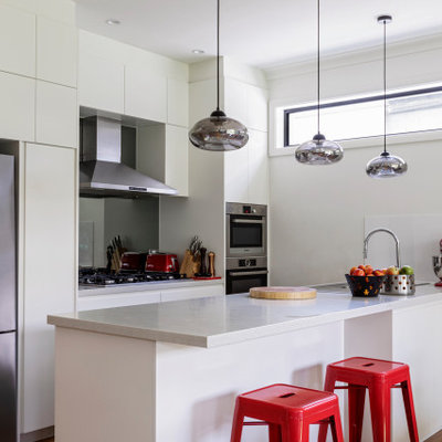 Inspiration for a contemporary galley medium tone wood floor and brown floor kitchen remodel in Sydney with flat-panel cabinets, white cabinets, stainless steel appliances, a peninsula and white countertops