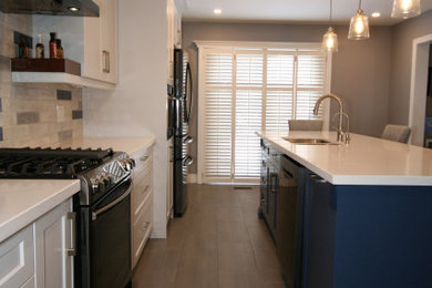 Kitchen - contemporary single-wall ceramic tile kitchen idea with an undermount sink, shaker cabinets, blue cabinets, multicolored backsplash, subway tile backsplash, black appliances and white countertops