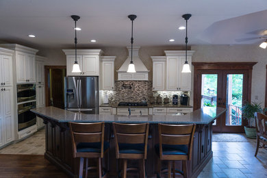 Exempel på ett mellanstort klassiskt kök, med luckor med upphöjd panel, vita skåp, granitbänkskiva, flerfärgad stänkskydd, stänkskydd i stickkakel, rostfria vitvaror, kalkstensgolv, en köksö och en undermonterad diskho