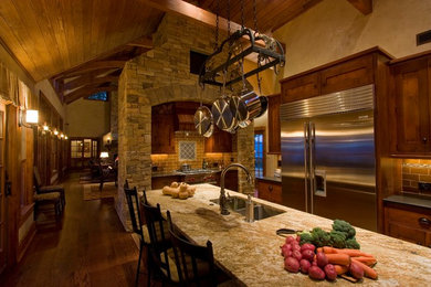 Eat-in kitchen - rustic galley dark wood floor eat-in kitchen idea in Boston with a double-bowl sink, recessed-panel cabinets, dark wood cabinets, granite countertops, brown backsplash, stainless steel appliances and an island