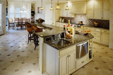 Große Küche mit profilierten Schrankfronten, weißen Schränken, Granit-Arbeitsplatte, Keramikboden und Kücheninsel in Sonstige