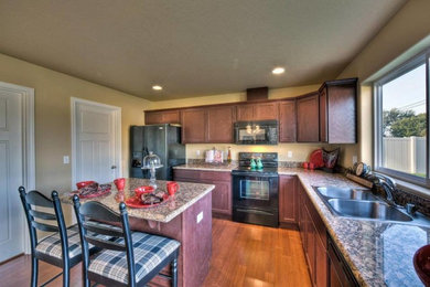 Example of a classic l-shaped medium tone wood floor eat-in kitchen design in Boise with a drop-in sink, shaker cabinets, dark wood cabinets, granite countertops, stainless steel appliances and an island