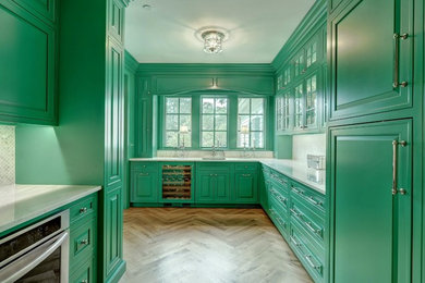 Foto de cocinas en U ecléctico grande con suelo de madera en tonos medios, puertas de armario verdes, salpicadero blanco y suelo marrón