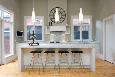Exempel på ett mellanstort modernt linjärt kök med öppen planlösning, med en dubbel diskho, skåp i shakerstil, vita skåp, marmorbänkskiva, vitt stänkskydd, stänkskydd i sten, rostfria vitvaror, ljust trägolv och en köksö