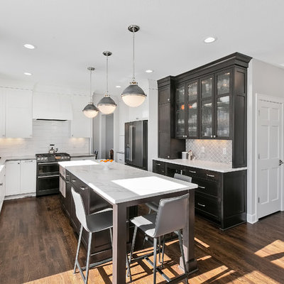 Eat-in kitchen - mid-sized transitional u-shaped brown floor and dark wood floor eat-in kitchen idea in Minneapolis with a farmhouse sink, white backsplash, an island, white countertops, recessed-panel cabinets, white cabinets, quartzite countertops, subway tile backsplash and stainless steel appliances