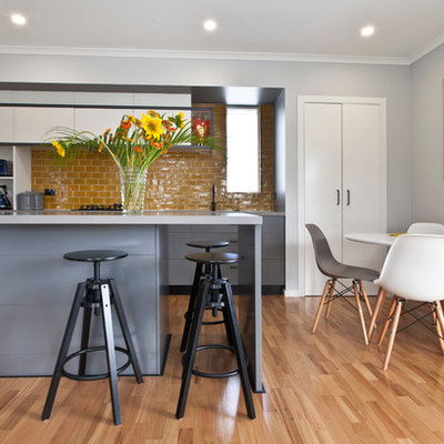 Eat-in kitchen - contemporary galley light wood floor eat-in kitchen idea in Sydney with flat-panel cabinets, gray cabinets, yellow backsplash and an island