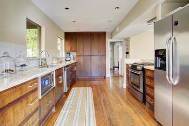 Modern inredning av ett mellanstort kök, med en nedsänkt diskho, släta luckor, skåp i mörkt trä, granitbänkskiva, vitt stänkskydd, stänkskydd i keramik, rostfria vitvaror, mellanmörkt trägolv, en köksö och brunt golv