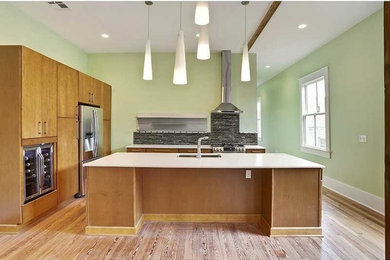 Inspiration for a large contemporary l-shaped light wood floor eat-in kitchen remodel in New Orleans with an island, flat-panel cabinets, medium tone wood cabinets, quartz countertops, gray backsplash, glass tile backsplash, stainless steel appliances and a double-bowl sink