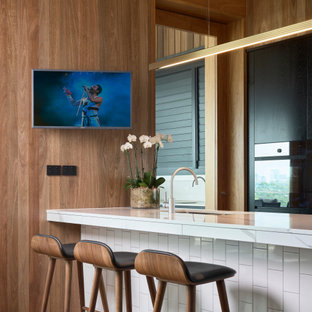 Inspiration for a contemporary kitchen in Brisbane with an undermount sink, flat-panel cabinets, black cabinets, medium hardwood floors, a peninsula and white benchtop.