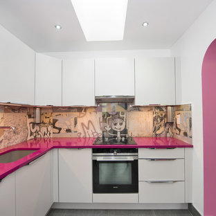 Immagine di una cucina a L eclettica di medie dimensioni con ante lisce, elettrodomestici in acciaio inossidabile, pavimento grigio, ante bianche, paraspruzzi multicolore e top rosa