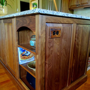 Mid-sized elegant l-shaped medium tone wood floor open concept kitchen photo in Charlotte with a double-bowl sink, raised-panel cabinets, dark wood cabinets, granite countertops, beige backsplash, ceramic backsplash, stainless steel appliances and an island