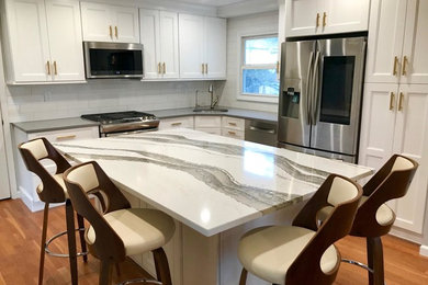 Mid-sized trendy u-shaped medium tone wood floor and brown floor eat-in kitchen photo in New York with an undermount sink, recessed-panel cabinets, white cabinets, quartzite countertops, white backsplash, subway tile backsplash, stainless steel appliances, an island and gray countertops