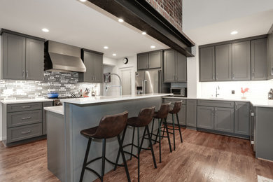 Large transitional galley medium tone wood floor and brown floor open concept kitchen photo in DC Metro with an undermount sink, shaker cabinets, gray cabinets, quartz countertops, multicolored backsplash, stone tile backsplash, stainless steel appliances, an island and white countertops