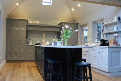 Medium sized traditional l-shaped kitchen/diner in West Midlands with a belfast sink, beaded cabinets, quartz worktops, medium hardwood flooring and an island.