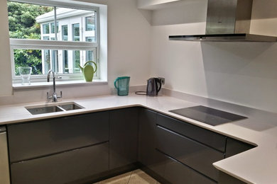 This is an example of a medium sized modern u-shaped enclosed kitchen in Other with an integrated sink, flat-panel cabinets, black cabinets, composite countertops, stainless steel appliances, ceramic flooring and no island.