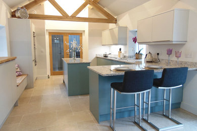 Bild på ett mellanstort funkis grå grått kök, med en nedsänkt diskho, släta luckor, blå skåp, bänkskiva i kvartsit, svarta vitvaror, kalkstensgolv, en köksö och grått golv