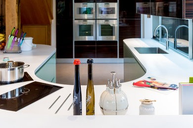 Idee per una cucina minimalista di medie dimensioni con lavello sottopiano, ante lisce, ante verdi, top in superficie solida, paraspruzzi con lastra di vetro e elettrodomestici in acciaio inossidabile