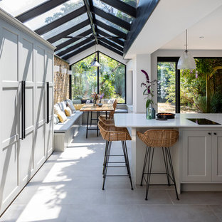 Idee per una cucina abitabile classica con ante in stile shaker, top in superficie solida, isola, pavimento grigio, ante grigie e top bianco