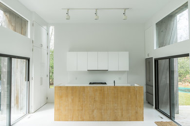 Inspiration for a mid-sized modern u-shaped white floor and painted wood floor open concept kitchen remodel in New York with flat-panel cabinets, white cabinets, white backsplash, an island and stainless steel appliances