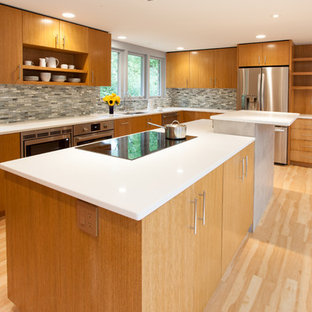 Design ideas for a mid-sized midcentury u-shaped kitchen in Milwaukee with an undermount sink, flat-panel cabinets, medium wood cabinets, quartz benchtops, black splashback, porcelain splashback, stainless steel appliances, vinyl floors and with island.
