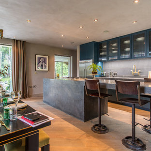 Inspiration for a medium sized urban single-wall open plan kitchen in London with glass-front cabinets, concrete worktops, grey splashback, stainless steel appliances, light hardwood flooring, an island and beige floors.