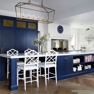 This is an example of a transitional kitchen in Melbourne with shaker cabinets, blue cabinets, white splashback, light hardwood floors, with island and white benchtop.
