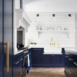 Inspiration for a traditional l-shaped kitchen in Melbourne with a farmhouse sink, shaker cabinets, blue cabinets, white splashback, coloured appliances, medium hardwood floors, with island, brown floor and white benchtop.