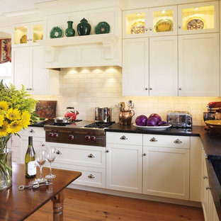 Diseño de cocina tradicional con armarios estilo shaker, puertas de armario blancas, salpicadero beige, salpicadero de azulejos tipo metro, electrodomésticos de acero inoxidable y encimera de esteatita