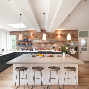 Idee per una grande cucina chic con lavello da incasso, ante lisce, ante grigie, top in cemento, elettrodomestici da incasso, pavimento in legno massello medio e penisola