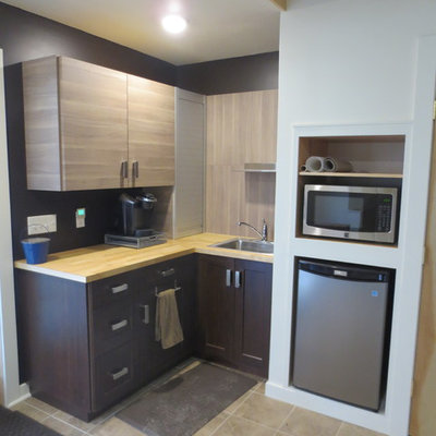 Small trendy l-shaped travertine floor enclosed kitchen photo in Philadelphia with a drop-in sink, shaker cabinets, dark wood cabinets, wood countertops, black backsplash, stainless steel appliances and no island