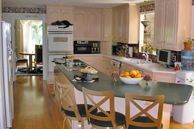 Large kitchen in Boston with white cabinets, white appliances and an island.