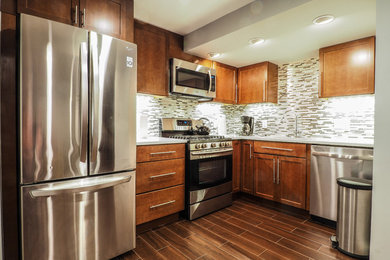 Inspiration for a mid-sized transitional l-shaped porcelain tile and brown floor kitchen remodel in DC Metro with an undermount sink, shaker cabinets, medium tone wood cabinets, quartz countertops, multicolored backsplash, matchstick tile backsplash, stainless steel appliances and no island