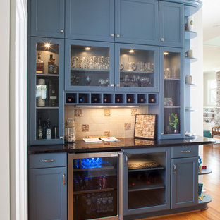 Medium sized traditional kitchen in Detroit with recessed-panel cabinets, beige splashback, medium hardwood flooring, ceramic splashback, stainless steel appliances, brown floors, blue cabinets and black worktops.