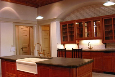 Example of a classic ceramic tile open concept kitchen design in Dallas with a farmhouse sink, glass-front cabinets, medium tone wood cabinets, granite countertops, white backsplash, porcelain backsplash and an island