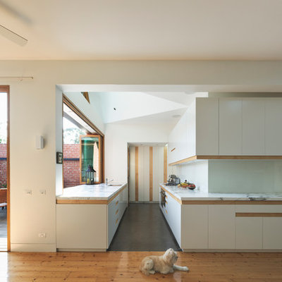 Inspiration for a huge contemporary galley concrete floor open concept kitchen remodel in Melbourne with flat-panel cabinets, white cabinets, an undermount sink, marble countertops, white backsplash, glass sheet backsplash, stainless steel appliances and no island