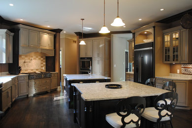 Example of a large classic u-shaped dark wood floor and brown floor open concept kitchen design in Cleveland with raised-panel cabinets, granite countertops, two islands, a farmhouse sink, beige cabinets, beige backsplash, ceramic backsplash and stainless steel appliances