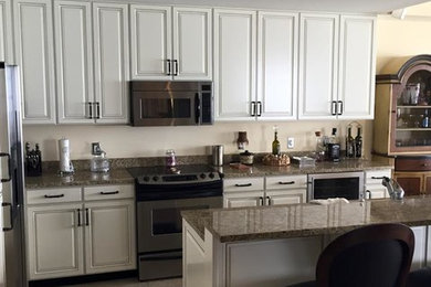 Inspiration for a mid-sized timeless l-shaped ceramic tile kitchen pantry remodel in Miami with an undermount sink, shaker cabinets, white cabinets, white backsplash, granite countertops, stainless steel appliances and an island