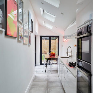 Inspiration for a small contemporary single-wall kitchen/diner in London with a submerged sink, flat-panel cabinets, white cabinets, integrated appliances, no island, grey floors and grey worktops.