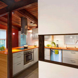 Foto de cocina en U, retro, de tamaño medio, abierta, con fregadero bajoencimera, armarios con paneles lisos, puertas de armario blancas, encimera de cuarzo compacto, salpicadero blanco, salpicadero de vidrio templado, electrodomésticos de acero inoxidable, suelo de baldosas de porcelana, península, suelo gris y encimeras naranjas