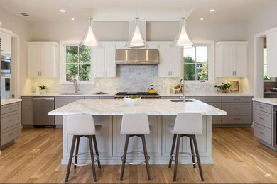 Mid-sized farmhouse u-shaped medium tone wood floor and beige floor kitchen photo in San Francisco with an undermount sink, shaker cabinets, gray cabinets, marble countertops, white backsplash, stone slab backsplash, stainless steel appliances and an island