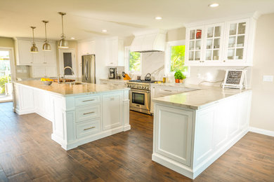 Example of a large trendy u-shaped dark wood floor and brown floor kitchen design in San Diego with an undermount sink, shaker cabinets, white cabinets, marble countertops, white backsplash, stone slab backsplash, stainless steel appliances and an island