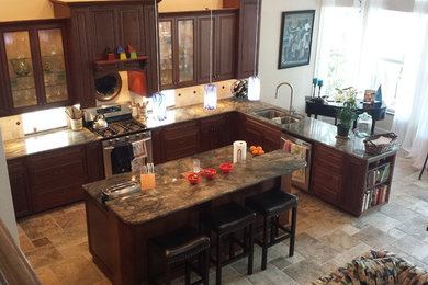Elegant kitchen photo in Tampa with raised-panel cabinets, dark wood cabinets and an island