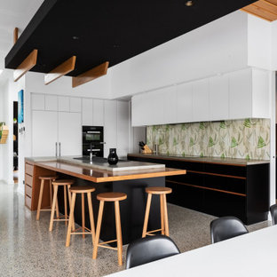 This is an example of a contemporary open plan kitchen in Canberra - Queanbeyan with flat-panel cabinets, white cabinets, multi-coloured splashback, black appliances, with island, multi-coloured floor and green benchtop.