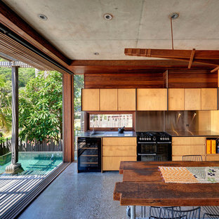 Design ideas for a tropical single-wall eat-in kitchen in Other with flat-panel cabinets, medium wood cabinets, black appliances, concrete floors, no island, grey floor and grey benchtop.
