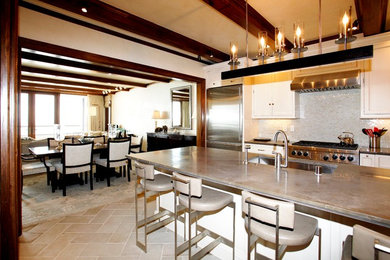 Example of a mid-sized transitional l-shaped porcelain tile eat-in kitchen design in Santa Barbara with recessed-panel cabinets, white cabinets, solid surface countertops, an island, an undermount sink, glass tile backsplash and stainless steel appliances